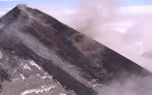 The eruption of a 8,261-foot volcano along the Alaska Peninsula southwest of Anchorage continues to dribble molten rock down its slopes, trigger steaming lahars and spit small ash clouds into the air.